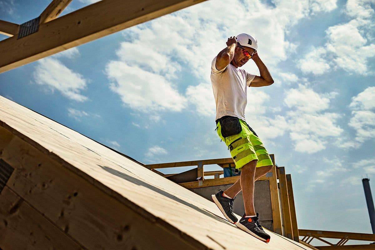 håndverker går ned fra et tak i solskinn