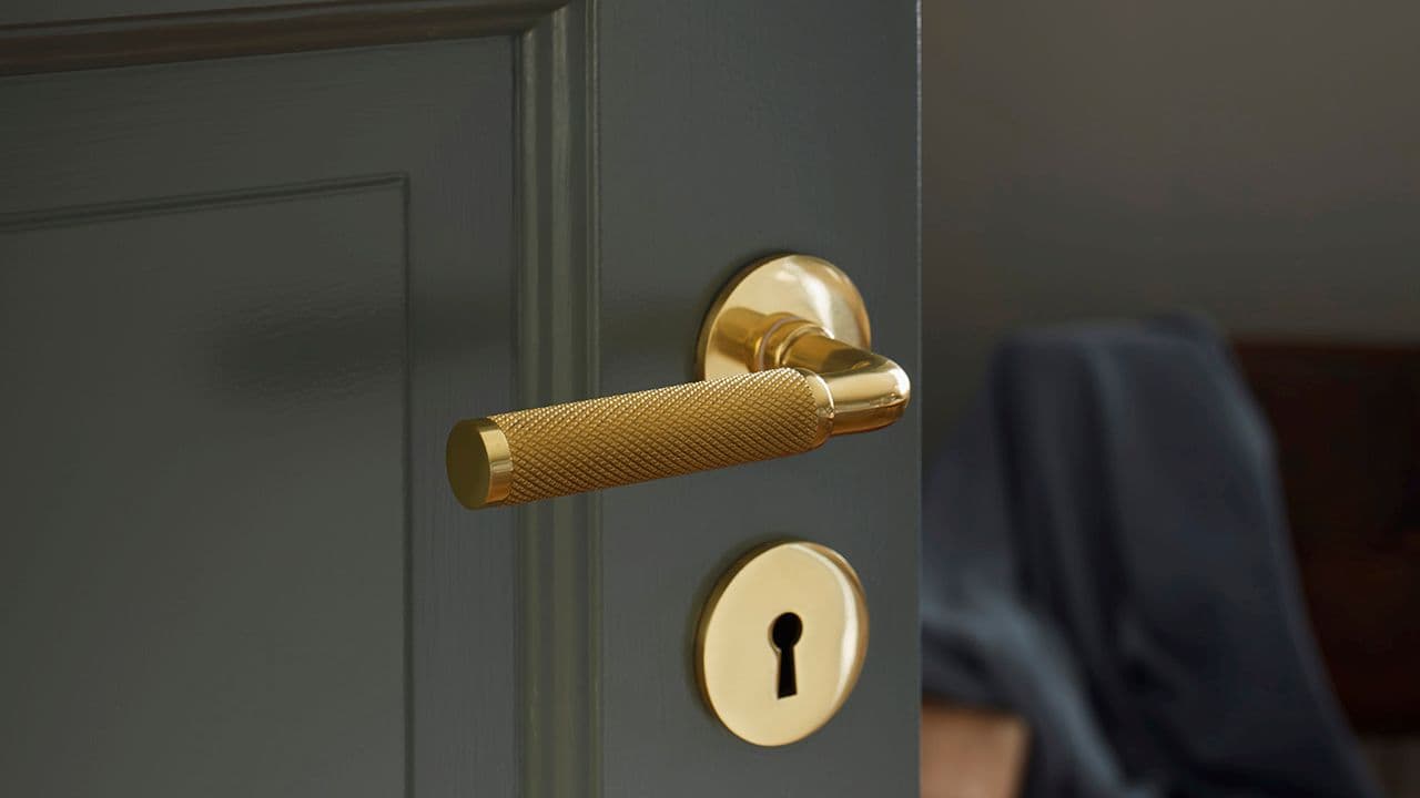 Messing dørhåndtak på sort innerdør.