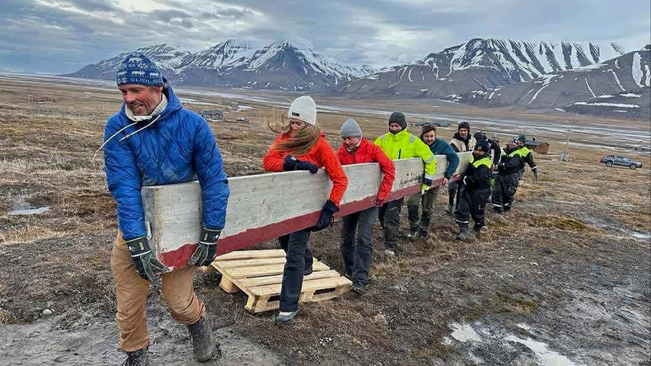 Flere mennesker som bærer en stor planke over en slette med fjell i bakgrunn