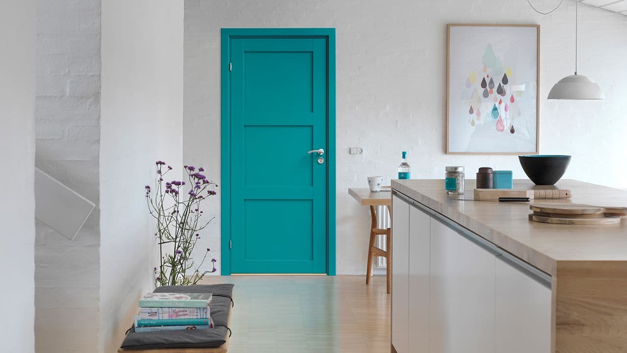 Turkis dør inne i hvitt kjøkken med hvite murvegger.