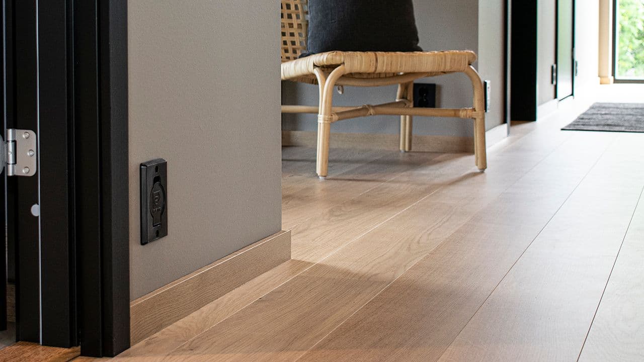 Dørkarm i dempet sort kombinert med glatt listeverk i eik.