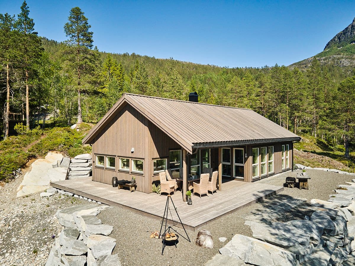 Stor moderne hytte på fjellet med bålpanne.
