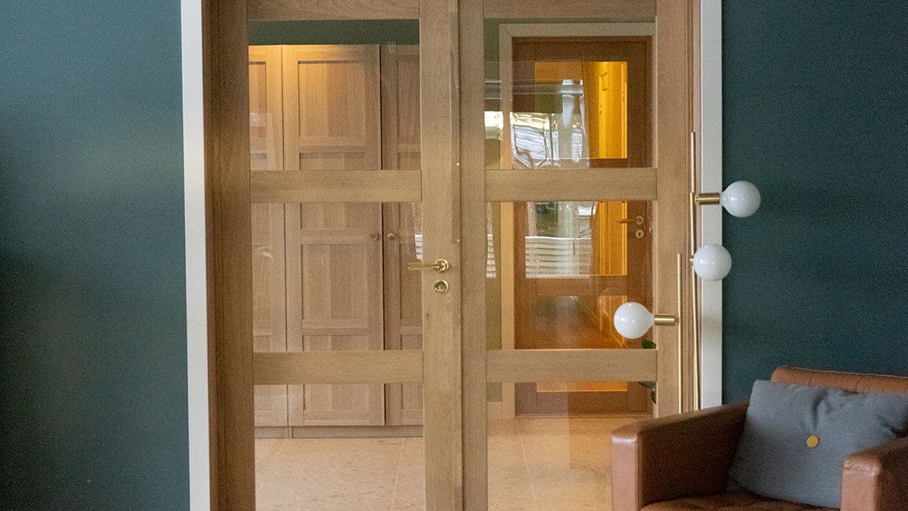 Grønn stue med tofløyet innerdør i eik med glass.