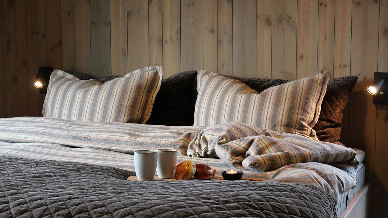 Oppredd seng med furupanel på veggene beiset med interiørbeis Gjøco Lindbergtinden 80004.