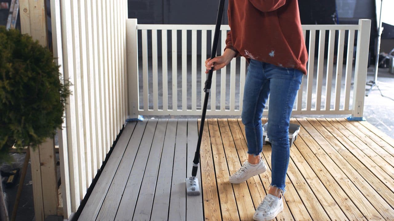 Kvinne som vedlikeholder terrasse med beis.