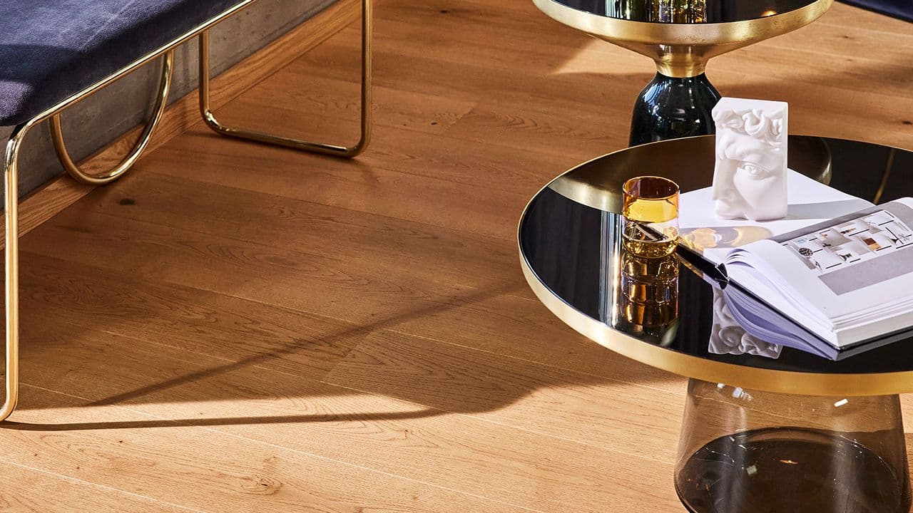 Tregulv i eik i stue med møbler i messing.