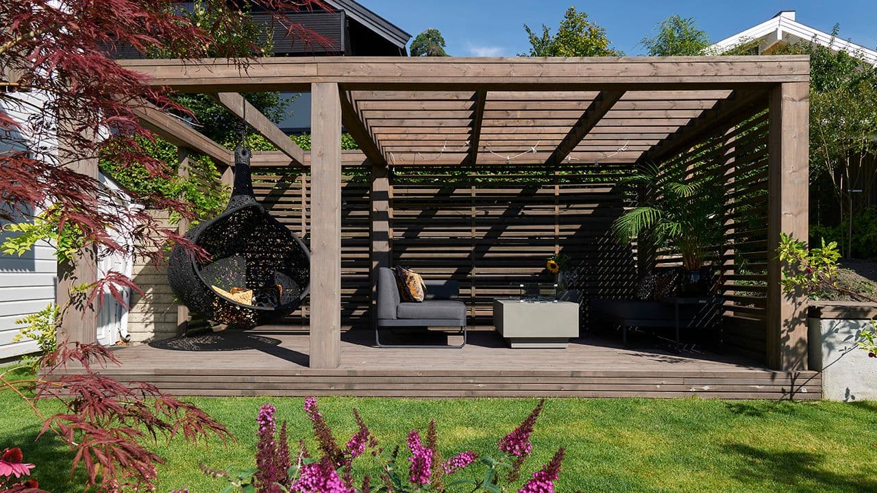 Pergola bygget med spilevegg med sittegruppe og hengestol.