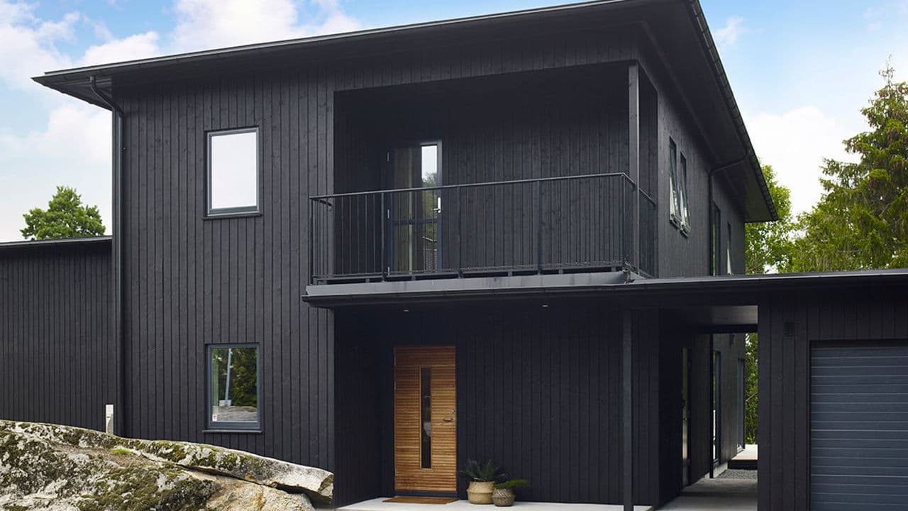 Hus med svart fabrikkmalt kledning.