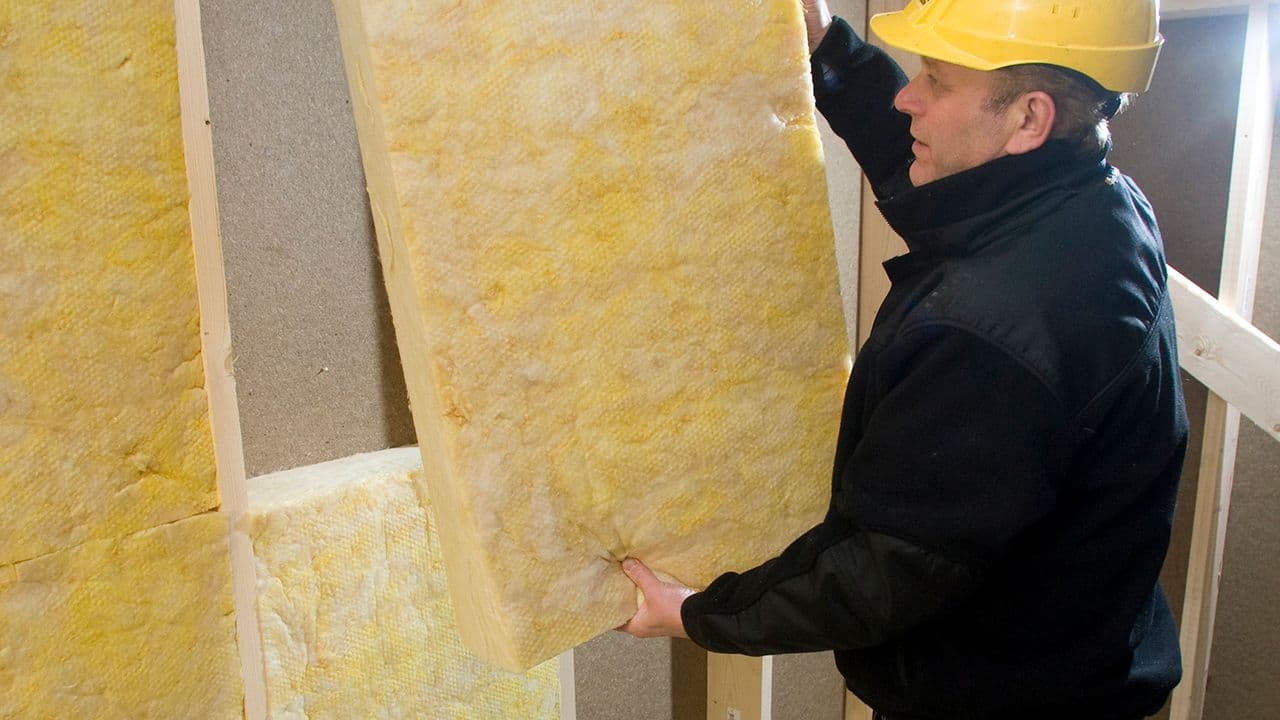 Mann som putter isolasjon i innvendig vegg.
