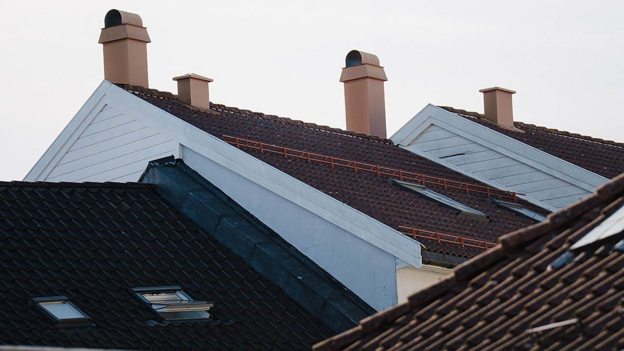 Toppen av hvite trehus med svarte og rød takstein på taket.