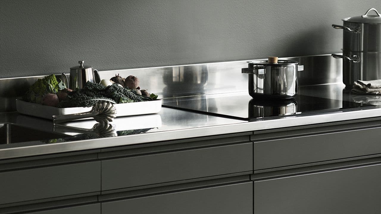 Nærbilde av grønt kjøkken med benkeplate i stål