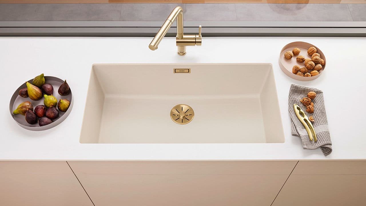 Blandebatteri i messing på kjøkken med lyse overflater.