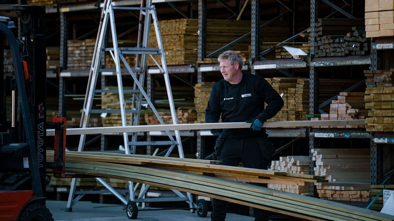 Byggtorget ansatt bærer terrassebord til kunde.