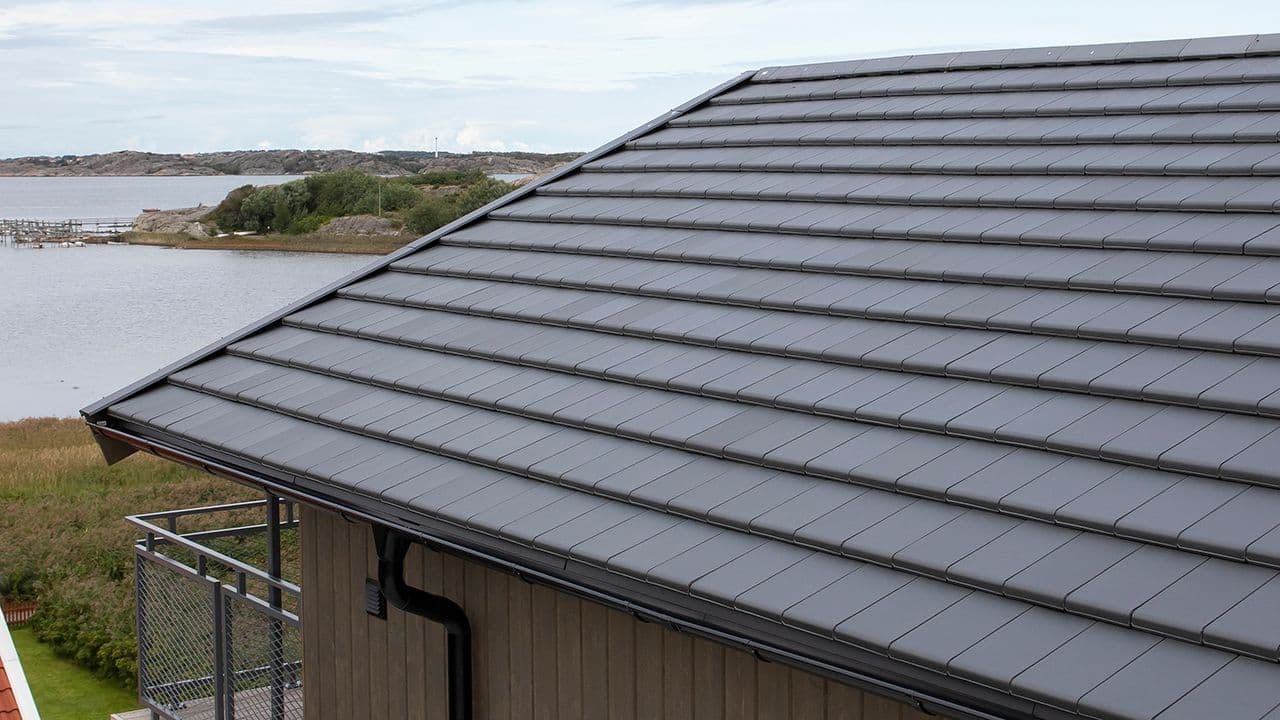 Flat takstein på hus ved sjøen.