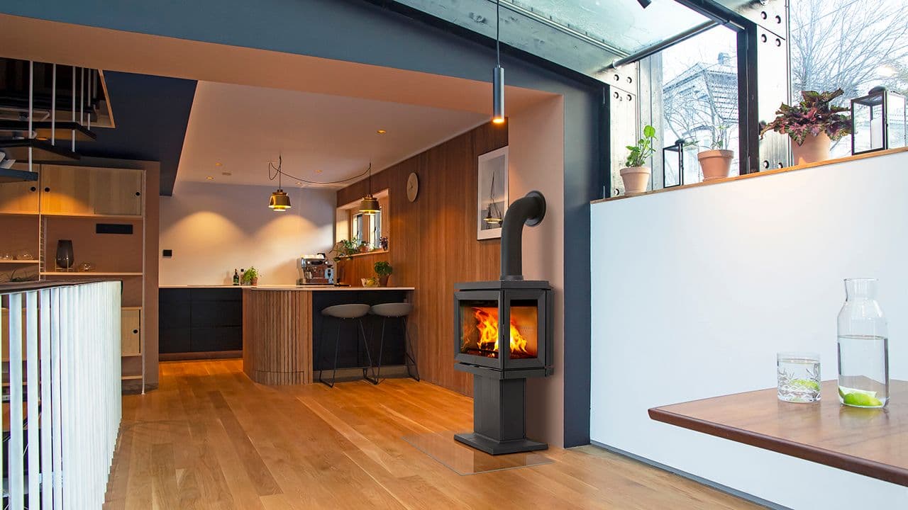 Støpejernsovn i åpen kjøkkenløsning i moderne hjem med spilevegg.