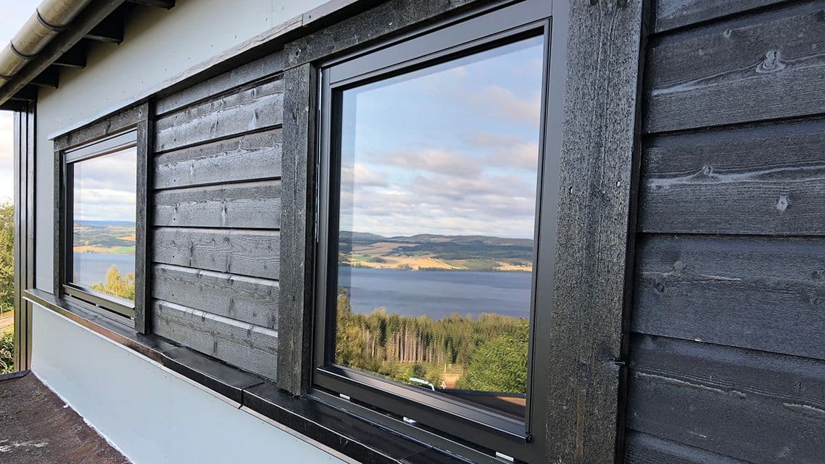 nærbilde av en husvegg med to vinduer og dobbelfalset kledning