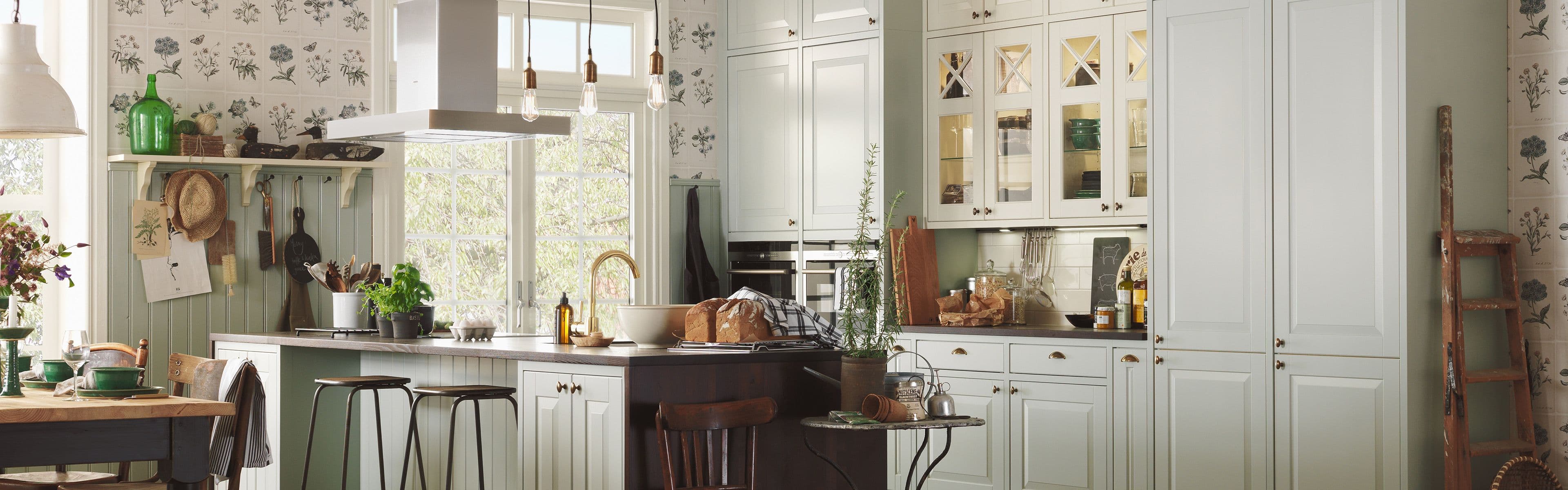 Landlig kjøkken med profilerte fronter, vitrinefronter på overskap og kjøkkenøy.