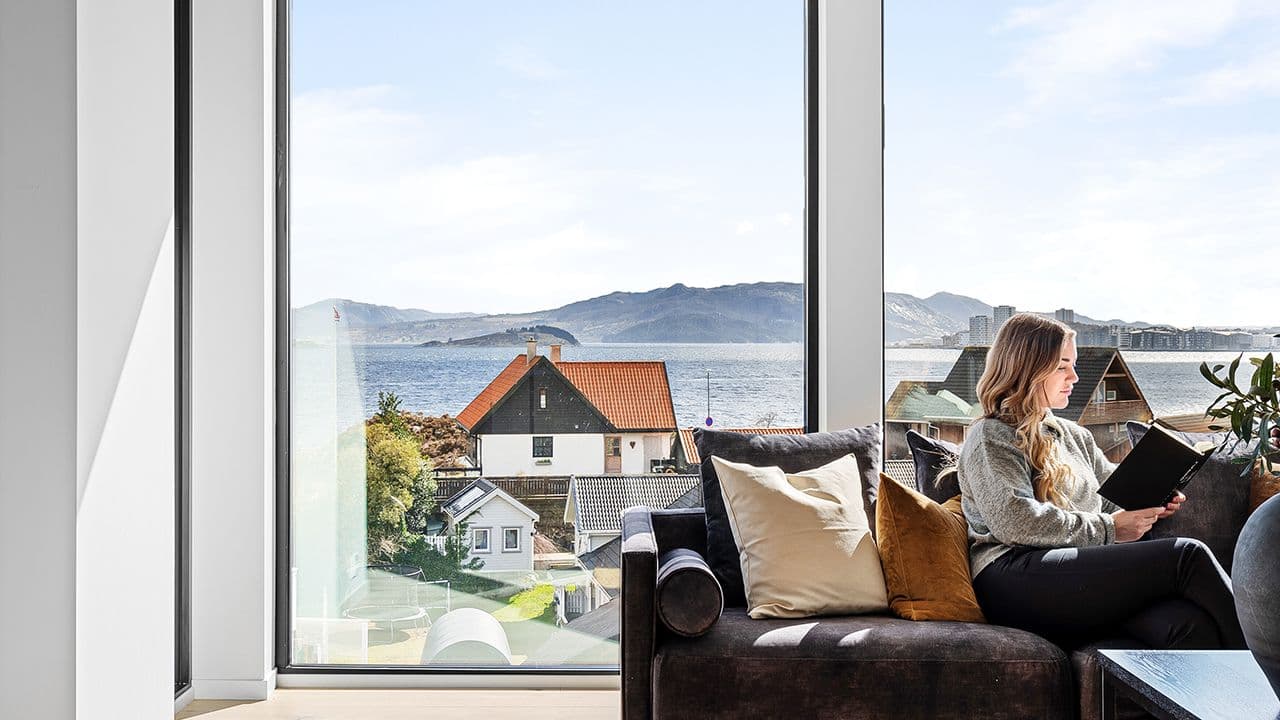 Store vindusflater med 3-lags glass i stue med en kvinne i sofaen.