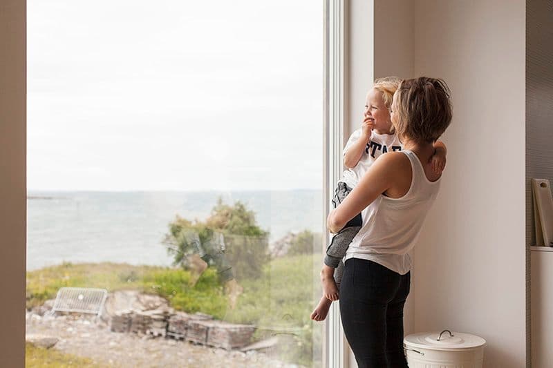 kvinne og barn ser ut av et stort vindu